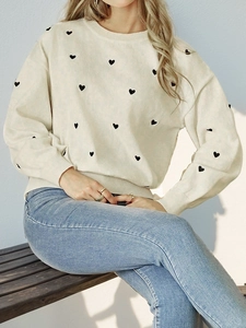 Women's cream knit sweater with black heart patterns and classic crewneck collar