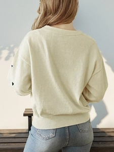 Beige knit sweater with black heart patterns on sleeves and ribbed crew neck for casual style