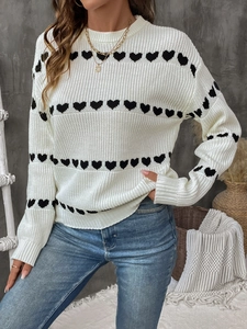 Close-up of heart pattern jacquard and ribbed knit texture on cream crewneck sweater