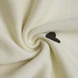 Close-up of knit fabric showing soft cream texture and detailed black heart embroidery