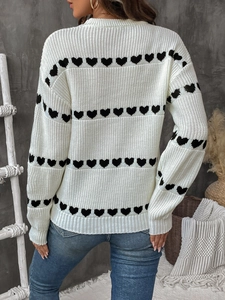 Detail view of the back of a women's cream knit sweater featuring black heart patterns