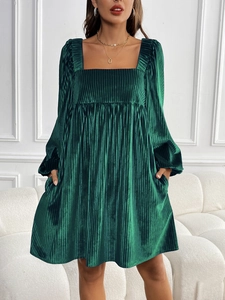 Détail de la robe en velours vert émeraude à col carré avec texture plissée et poches