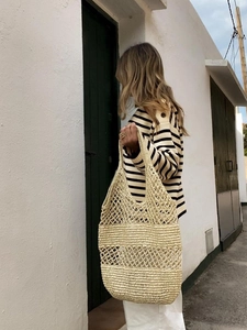 Detail of hand-woven straw tote bag showing open-knit texture and retro bohemian style