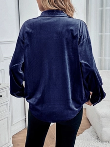 Back view of a deep blue velvet long sleeve shirt with a curved hem and glossy texture