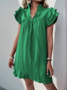 Detail of emerald green summer dress showing vertical pleated texture and ruffle sleeves