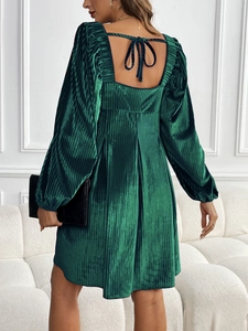 Détail de la robe en velours vert émeraude avec texture plissée et nœud dans le dos