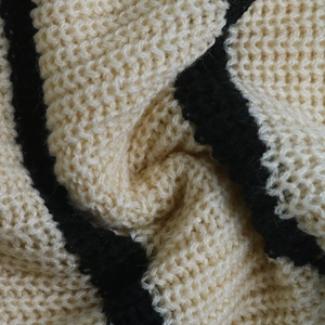 Vue macro de la maille épaisse d'un cardigan rayé en coloris beige et noir élégant