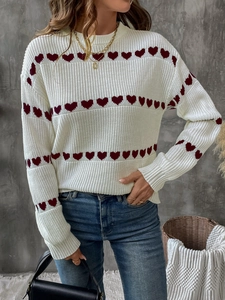 Detail of red heart jacquard patterns on white knit sweater with round neckline