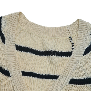Détail du col en V d'un gilet en maille beige à rayures horizontales noires et points texturés