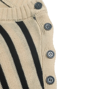 Detailed close-up of beige and black striped knit sweater with decorative side buttons
