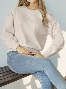 Detail of light pink knit sweater featuring ribbed cuffs and soft shoulder seams