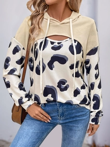 Detail of a beige cropped hoodie layered over a blue leopard print long sleeve top