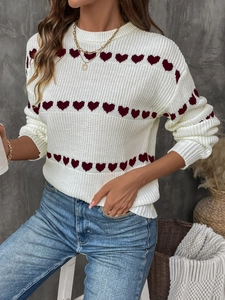 Close-up of white knit sweater featuring red heart patterns and chunky texture details
