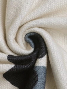 Macro shot of cream-colored knit fabric with black floral patterns and soft texture