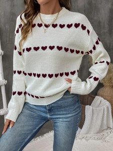Detailed view of white knit sweater featuring wine red heart patterns and cozy texture