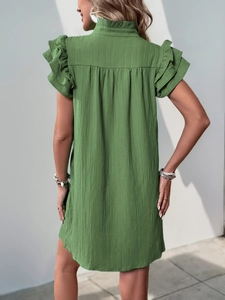 Close-up of grass green summer dress featuring vertical pleated texture and tiered ruffle sleeves