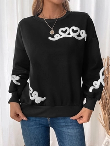 Close-up of black sweatshirt featuring white plush embroidery heart patterns and ribbed cuffs