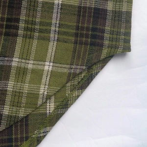 Detail shot of green plaid shirt fabric with neat overlock stitching on the hem