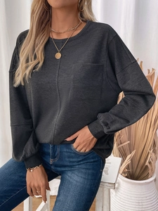 Detail of dark gray crewneck sweatshirt showing fabric texture and chest pocket