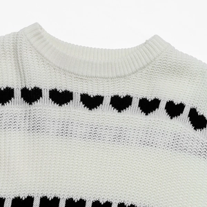 Detail of cream knit sweater with ribbed crew neck and black heart jacquard pattern