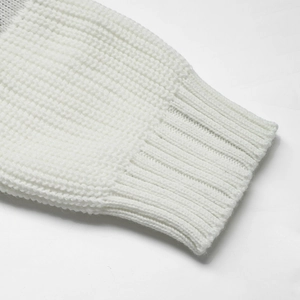 Close-up detail of white knitted sweater sleeve with ribbed cuff texture and soft yarn