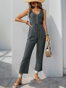 Detail view of dark grey textured jumpsuit featuring white buttons and drawstring waist