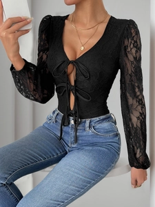 Close-up of elegant V-neck lace bodysuit featuring intricate crochet texture and bow ties