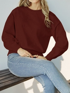 Close-up of a deep burgundy crew neck knitted sweater paired with blue denim jeans