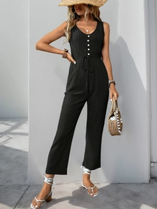 Detail of black textured sleeveless jumpsuit with front buttons and drawstring waist