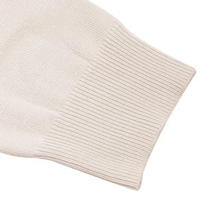 Detail view showing ribbed knit cuffs and soft cream fabric of the women sweater