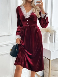 Détail d'une robe de soirée en velours bordeaux avec dentelle blanche et boutons perles