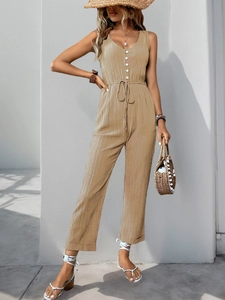 Detail of khaki textured jumpsuit with deep V-neck, white buttons and drawstring waist