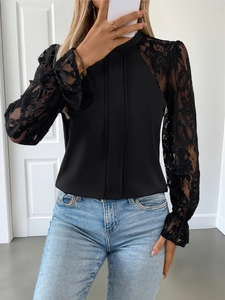 Detail of elegant black top showing intricate floral lace sleeves and pleated fabric texture
