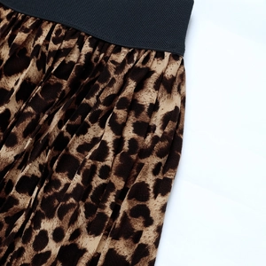 Detail of leopard print pleated skirt with black elastic waistband on white background