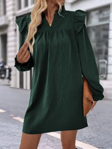 Close-up of deep green dress featuring ruffle trim V-neck and tiered shoulder details