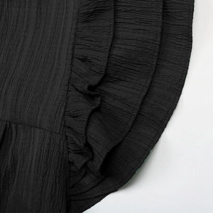 Detail showing vertical pleated texture and triple-layered ruffles on a black dress