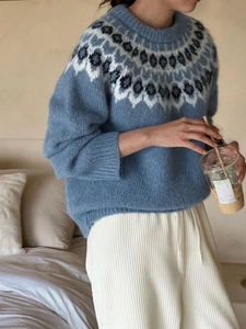 Dettaglio del motivo Fair Isle sul maglione blu a maglia con sfondo camera da letto accogliente