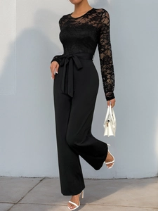 Detail view of a black jumpsuit with lace sleeves and a tie-waist bow accent
