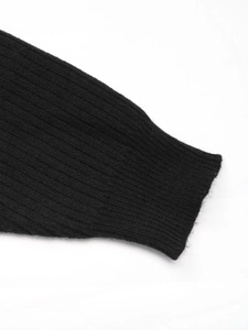 Gros plan des poignets en maille côtelée noire sur une robe pull à manches chauve-souris