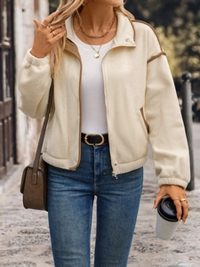 Detail of a cream fleece jacket featuring contrast brown piping and a metal zipper closure