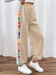 Detail of crochet rainbow floral stripes and drawstring waist on beige joggers