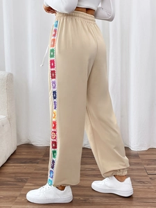 Detail of colorful geometric woven side stripes on beige casual drawstring joggers