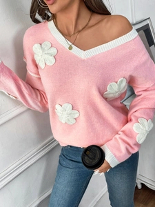 Détail d'un pull en maille rose avec col en V et appliqués floraux blancs en relief