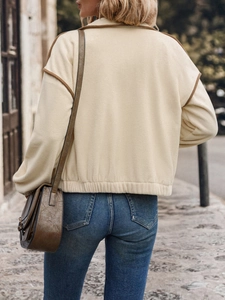 Close-up of beige fleece jacket with brown trim and vintage brown leather saddle bag
