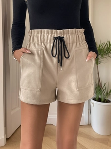 Detail of high-waist beige wool shorts featuring elastic waistband and black drawstring