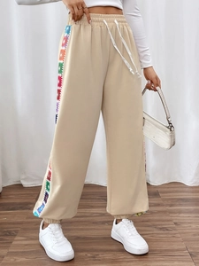 Detail of beige joggers featuring side colorful geometric patterns and drawstring waist