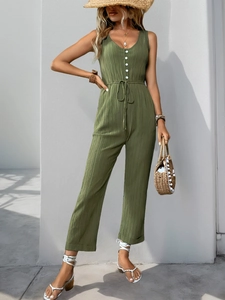 Detail of army green sleeveless jumpsuit with textured fabric and white button accents