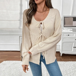 Detail of beige knit cardigan featuring bow tie closures and fine ribbed texture