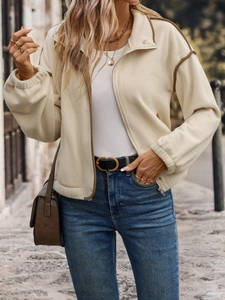 Close-up of cream fleece jacket with brown trim piping and stylish front zipper detail