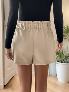 Back view of beige high-waisted wool shorts showing elastic ruffled waistband details